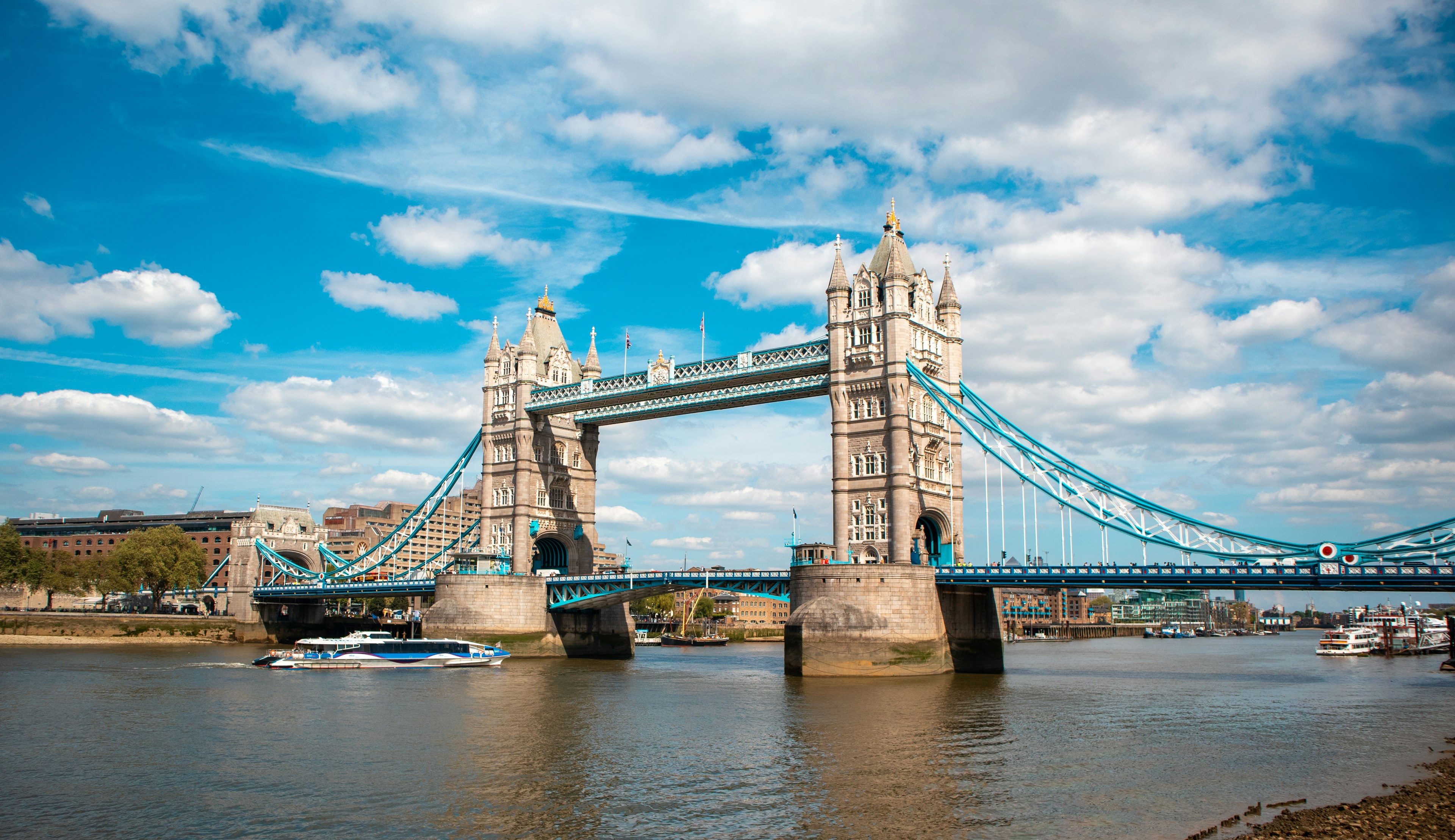 Tower Bridge over the River Thames, London, under a blue sky with white clouds